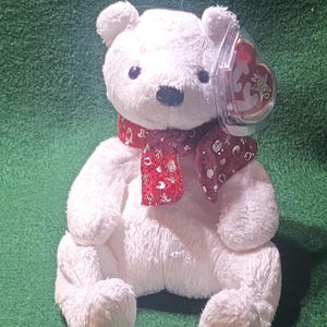 May include: White plush polar bear wearing a red and white polka dot scarf with a Ty Beanie Baby tag attached.