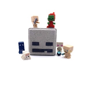 May include: A set of Minecraft character figurines, including a zombie, a skeleton, a spider, and three villagers. The figurines are made of plastic and are brightly colored. The figurines are arranged on a white background.