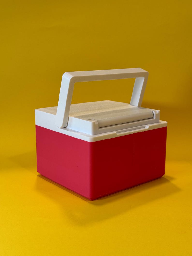 May include: A small, red and white cooler with a white handle. The cooler is closed and has a white lid.
