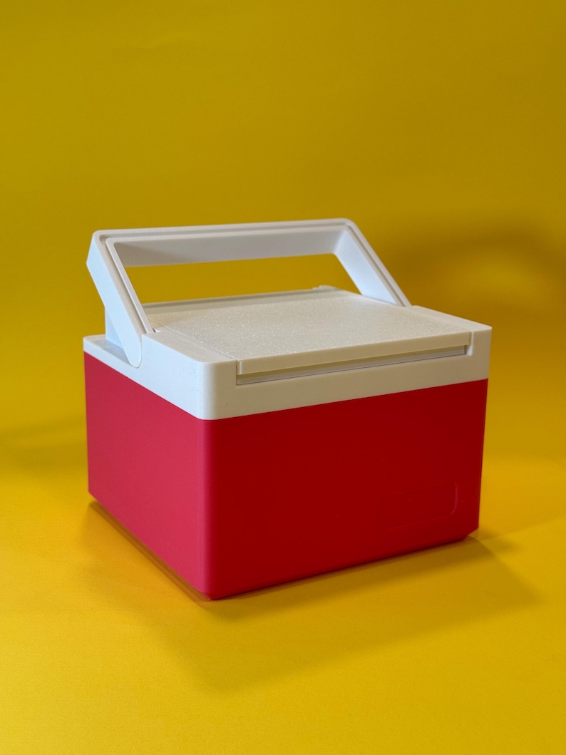 May include: A small, red and white cooler with a white handle. The cooler is made of plastic and has a rectangular shape.