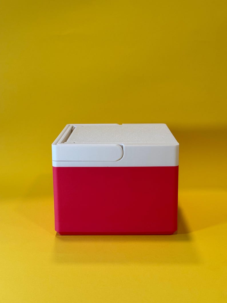 May include: A small, red and white cooler with a hinged lid. The cooler is made of plastic and has a smooth, glossy finish.