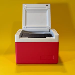 May include: A red and white cooler with the lid open. The cooler has a white interior and a black handle.