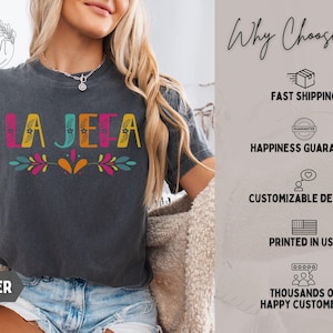 May include: Dark grey t-shirt with the word "LA JEFA" in colourful letters and floral accents. The shirt also has the word "PEPPER" printed at the bottom. The image also includes text that says "Why Choose Us".