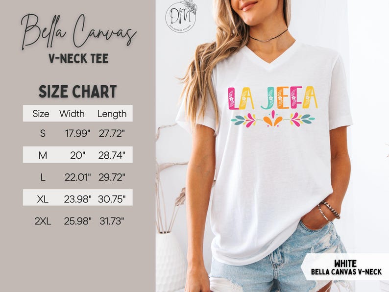 May include: White Bella Canvas V-neck tee with the text "LA JEFA" in colourful letters. The shirt has a size chart with measurements in inches. The tee features a floral design and is a casual wear item.