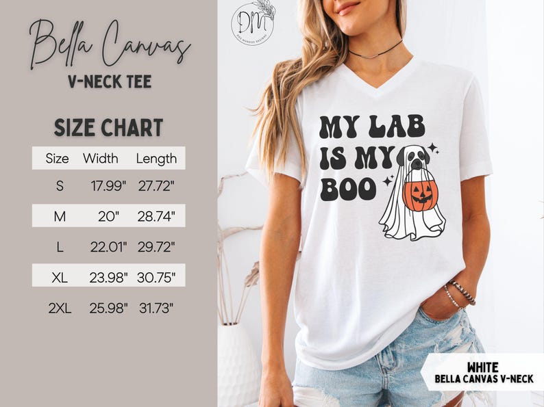 May include: A white V-neck t-shirt featuring a black graphic of a Labrador retriever wearing a ghost costume and holding an orange jack-o'-lantern bucket. The text reads MY LAB IS MY BOO. A size chart displays widths and lengths in centimetres.