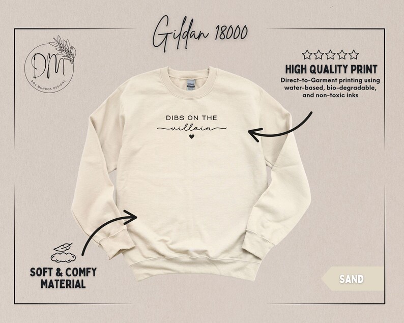 May include: Sand-colored Gildan 18000 sweatshirt with the phrase "DIBS ON THE villain" printed in black script. The sweatshirt features a crew neck and long sleeves. The image also highlights the soft and comfy material and high-quality print.