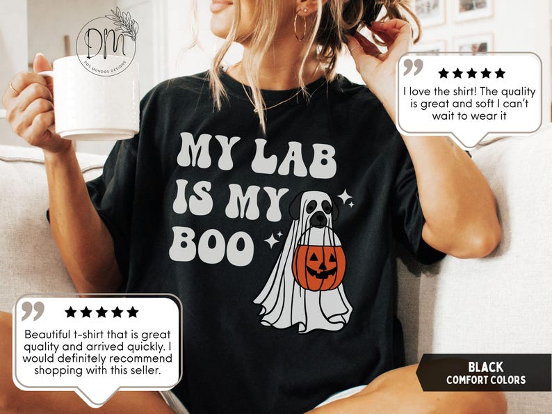 May include: A black t-shirt featuring the white text "MY LAB IS MY BOO" and a graphic of a Labrador dog wearing a white ghost costume while holding an orange jack-o'-lantern pumpkin bucket, accented with small white four-pointed star icons.
