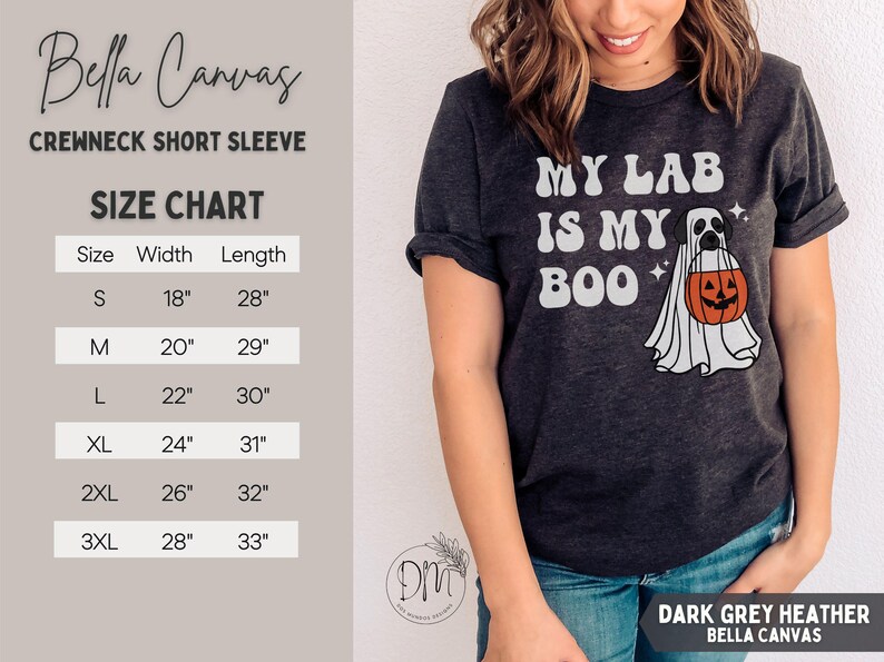 May include: A dark grey heather short-sleeve crewneck t-shirt featuring a graphic of a dog dressed as a ghost holding an orange jack-o'-lantern bucket with the text 'MY LAB IS MY BOO'. A size chart with width and length in inches is visible.