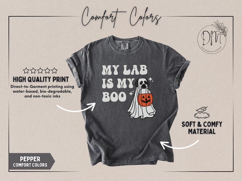 May include: A charcoal grey short-sleeve t-shirt featuring a graphic of a Labrador retriever wearing a white ghost costume and holding an orange jack-o'-lantern bucket. The text reads MY LAB IS MY BOO in white letters with small star accents.