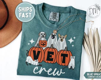 Könnte beinhalten: Ein blau-fichtenfarbenes T-Shirt mit einer Grafik von drei als Geister verkleideten Hunden hinter drei orangefarbenen Kürbissen. Die Kürbisse sind mit den schwarzen Buchstaben V, E und T versehen. Darunter steht das Wort crew in weißer Schreibschrift.