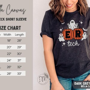 May include: A dark grey heather crewneck short sleeve t-shirt featuring a graphic of two orange pumpkins with the letters E and R, surrounded by three white ghosts, bats, and stars, with the text tech below. Includes a size chart in inches.