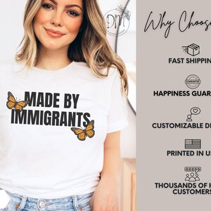 Pu&ograve; includere: Una t-shirt bianca a maniche corte con la scritta nera "MADE BY IMMIGRANTS" centrata sul petto, affiancata da due illustrazioni di farfalle monarca arancioni e nere. La t-shirt &egrave; abbinata a un paio di jeans blu.