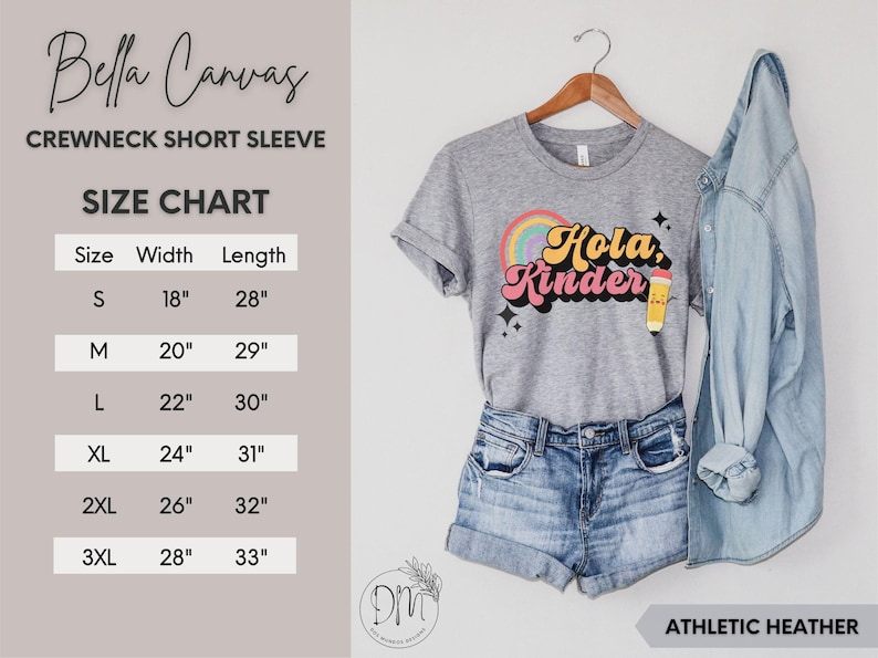 May include: A heather gray crewneck short sleeve t-shirt featuring a colorful graphic with a rainbow, a yellow pencil, and the text "Hola, Kinder" in a retro font. A size chart is provided with measurements in inches for sizes S through 3XL.