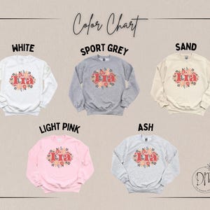 May include: A color chart displays five sweatshirts in white, sport grey, sand, light pink, and ash. Each sweatshirt features the word "Tia" in a floral design. The text "Color Chart" is at the top of the image.