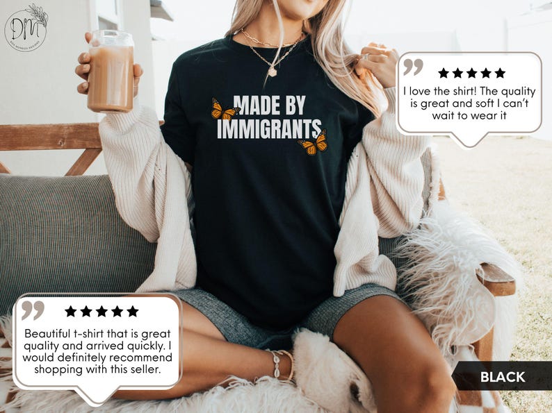 Pu&ograve; includere: Una t-shirt nera a maniche corte con la scritta bianca "MADE BY IMMIGRANTS" sul petto, affiancata da due illustrazioni di farfalle monarca arancioni e nere. Il capo &egrave; abbinato a un cardigan color crema e a pantaloncini grigi.