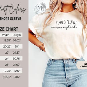 K&ouml;nnte beinhalten: Elfenbeinfarbenes Comfort Colors Kurzarm-T-Shirt mit dem Text "HABLO FLUENT spanglish". Die Gr&ouml;&szlig;entabelle zeigt die Ma&szlig;e in Zentimetern. Das T-Shirt wird von einer Person in Jeans getragen.