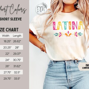 Puede incluir: Camiseta de manga corta de color marfil con la palabra "LATINA" en letras de bloque coloridas. La camiseta presenta un dise&ntilde;o floral debajo de la palabra. Se puede ver una tabla de tallas, con medidas en pulgadas para las tallas S a 4XL. La camiseta es de la marca Comfort Colors.
