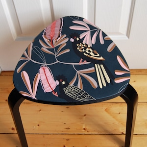 May include: A black stool with a dark blue, floral patterned seat featuring black birds and pink flowers. The stool has black legs.