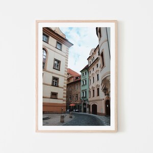 K&ouml;nnte beinhalten: Eine enge Gasse in Prag, Tschechien, mit bunten Geb&auml;uden auf beiden Seiten. Die Geb&auml;ude sind ein Mix aus Pastellfarben, darunter Rosa, Gelb und Gr&uuml;n. Die Gasse ist gepflastert und es sind ein paar Leute unterwegs.