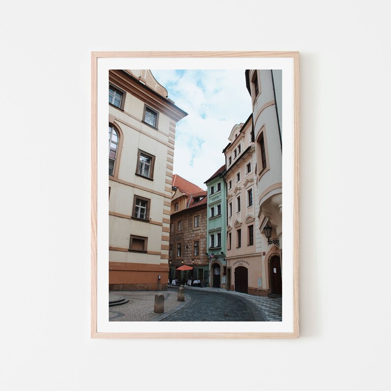 K&ouml;nnte beinhalten: Eine enge Gasse in Prag, Tschechien, mit bunten Geb&auml;uden auf beiden Seiten. Die Geb&auml;ude sind ein Mix aus Pastellfarben, darunter Rosa, Gelb und Gr&uuml;n. Die Gasse ist gepflastert und es sind ein paar Leute unterwegs.