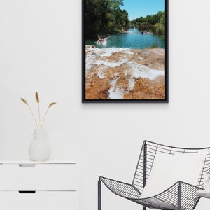 Może przedstawiać: Zdjęcie w ramie przedstawiające mężczyznę skaczącego do rzeki z wodospadem w tle. Woda jest jasnoniebieska, a skały jasnobrązowe. Niebo jest błękitne.