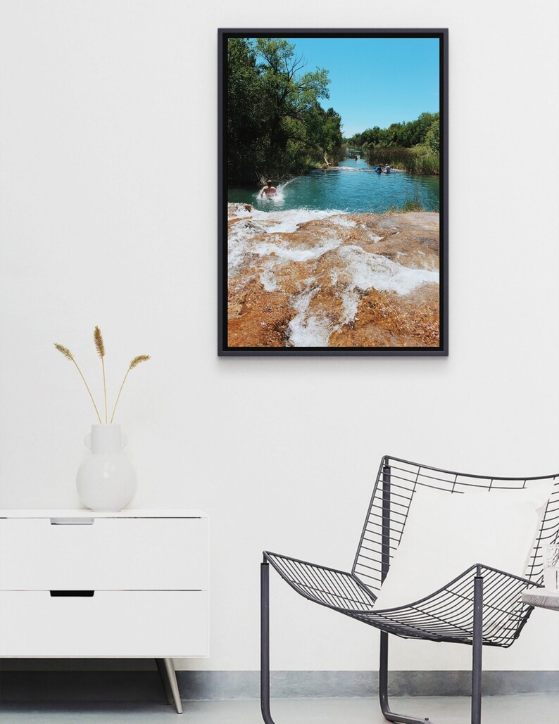 Może przedstawiać: Zdjęcie w ramie przedstawiające mężczyznę skaczącego do rzeki z wodospadem w tle. Woda jest jasnoniebieska, a skały jasnobrązowe. Niebo jest błękitne.