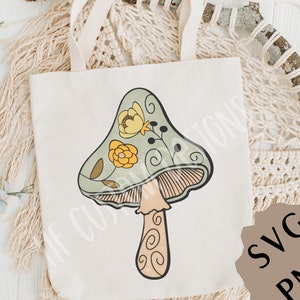 May include: A green and yellow mushroom with floral details on a white tote bag. The mushroom has a brown stem with a swirl pattern. The tote bag has a brown handle.