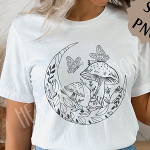 Op de afbeelding: Een wit T-shirt met een zwart-wit grafisch ontwerp van een halve maan met paddenstoelen en vlinders.