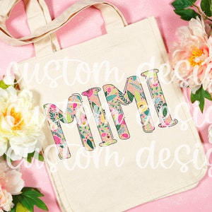 Pu&ograve; includere: Una borsa di tela bianca con un design floreale che compone la parola "MIMI".