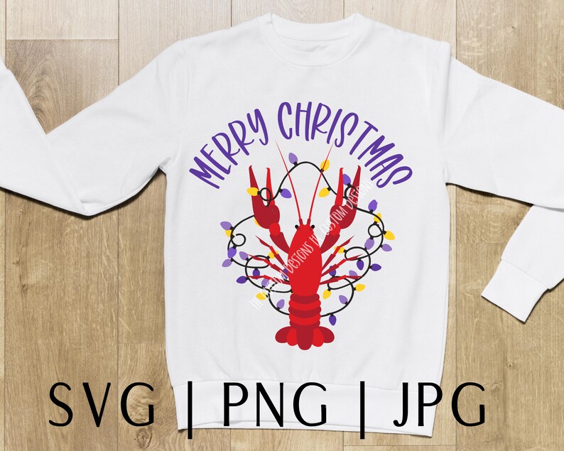 May include: White long-sleeved sweatshirt with the text "Merry Christmas" in purple lettering. A red crawfish with purple and yellow Christmas lights is in the center of the shirt.