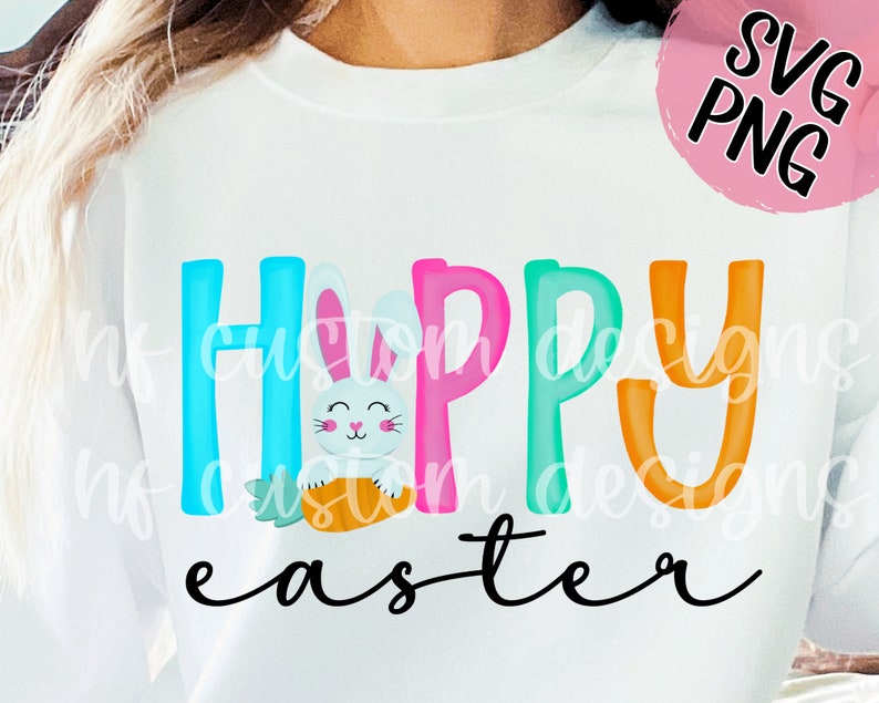 May include: A white sweatshirt with the text "Happy Easter" in colorful letters. A cartoon bunny holding a carrot is in the middle of the word "Happy".