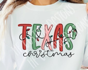 Puede incluir: Sudadera blanca con el texto "Texas Christmas" en letras rojas, verdes y rosas con un corazón y luces de cadena.