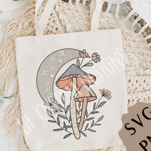 May include: A tote bag with a design of two mushrooms with orange and pink caps, a crescent moon with stars, and floral accents. The design is in a boho style.
