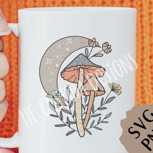 May include: White ceramic mug with a whimsical illustration of two mushrooms with orange and gray caps, growing from green foliage under a crescent moon with stars. The design is in a vintage style.