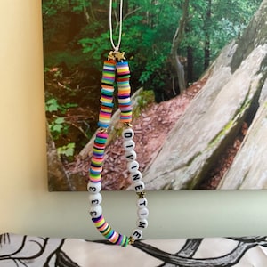 May include: A colourful beaded necklace with the words "DIVINE TIME" and the number "333" spelled out in white beads.