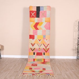 May include: A colorful geometric patterned runner rug with pink, red, yellow, and blue accents. The rug has a fringe border.