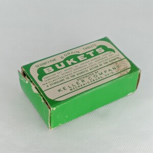 K&ouml;nnte beinhalten: Eine gr&uuml;ne Schachtel mit wei&szlig;em Text, der "Seventy-five 5 Grain Tablets Bukets Contains Ext. Buchu, Oil Juniper Berries, Lithion Carbonate, Extract Asparagus, Ext. Scoparios, Ext. Saw Palmetto Berries, Potassium Nitrate, Caffeine Alkaloid A Stimulant to the Diuretic Action of the Kidneys Distributed by Keller Company Mechanicsburg, Ohio." lautet.