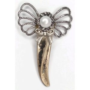 May include: A vintage silver-tone angel pin with a pearl center and bow detail. The angel has detailed wings and a feather-like design on the lower portion. The pin is likely made of metal and is a decorative accessory.