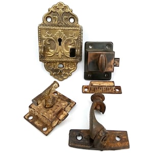 May include: An assortment of antique brass and metal hardware pieces, including ornate door latches and a decorative lock. The hardware features intricate designs and a weathered patina, showcasing their age and vintage appeal.