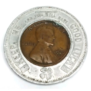 May include: A silver-colored good luck token with a copper penny at the center. The penny is dated 1960 and features the words "Liberty" and "In God We Trust." The token has the words "Keep Me And You Will Have Good Luck" and a four-leaf clover.