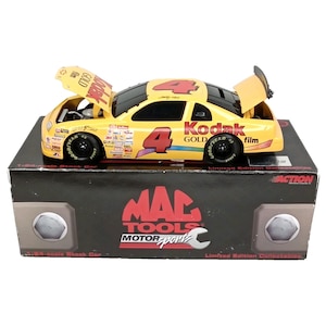 May include: A yellow 1/24 scale diecast stock car with the number 4 on the side. The car is sponsored by Kodak Gold film and Mac Tools Motorsports. The car has a black base and a black box with the Mac Tools Motorsports logo.