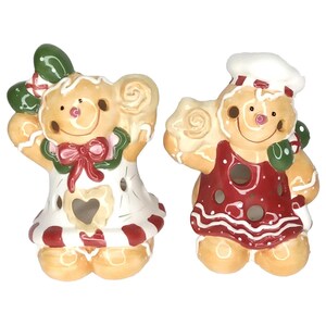 May include: Two ceramic gingerbread figures, one a woman and the other a chef. The woman wears a white dress with red accents and a red bow. The chef wears a red apron and a white chef's hat. Both figures have a light brown base color.