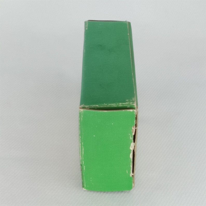 K&ouml;nnte beinhalten: Eine gr&uuml;ne Pappbox mit einem wei&szlig;en Etikett. Die Box ist rechteckig und hat ein schlichtes Design.