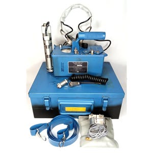 May include: A blue metal box containing a radiation detection kit. The kit includes a meter, a cylindrical device, a headset, a shoulder strap, and other components. The box has a yellow label and the text "U.S. AIR FORCE".