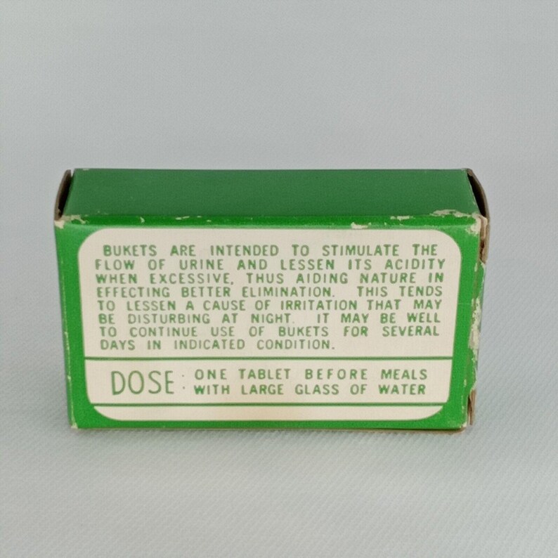K&ouml;nnte beinhalten: Gr&uuml;ne Schachtel mit wei&szlig;em Text, der die Verwendung von "Bukets" -Tabletten zur Stimulation des Harnflusses und zur Reduzierung der S&auml;ure beschreibt. Die Schachtel enth&auml;lt auch Dosierungsanweisungen: "Eine Tablette vor den Mahlzeiten mit einem gro&szlig;en Glas Wasser."