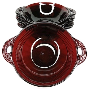 May include: A set of six ruby red glass bowls. Each bowl has two handles with decorative swirls and a ribbed design around the rim. The bowls are stacked, showcasing their deep color and elegant shape.