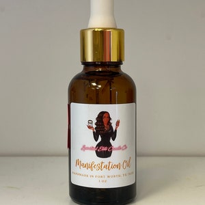 May include: A brown glass bottle with a gold lid and a white dropper top. The bottle is labeled "Manifestation Oil" and "Sparkled Elite Candle Co.". The label also includes the text "Handmade in Fort Worth, TX 76132" and "1 oz."