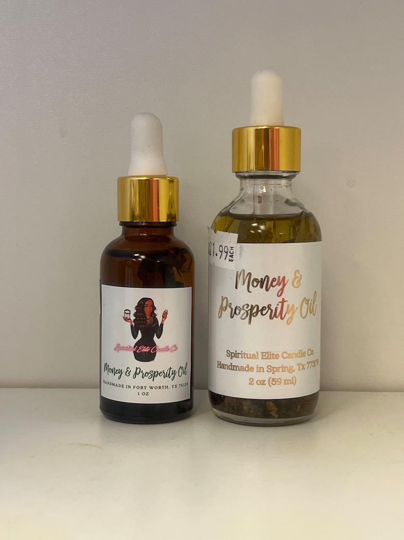 Peut inclure: Deux flacons en verre ambr&eacute; avec des bouchons dor&eacute;s et des compte-gouttes blancs remplis d'un liquide fonc&eacute;. Les deux flacons ont des &eacute;tiquettes blanches avec des lettres dor&eacute;es. L'&eacute;tiquette du plus grand flacon indique "Money & Prosperity Oil" et "Spiritual Elite Candle Co Handmade in Spring, Tx 77373 2 oz (59 ml)". L'&eacute;tiquette du plus petit flacon indique "Money & Prosperity Oil" et "Handmade in Fort Worth, Tx 76133 1 oz".