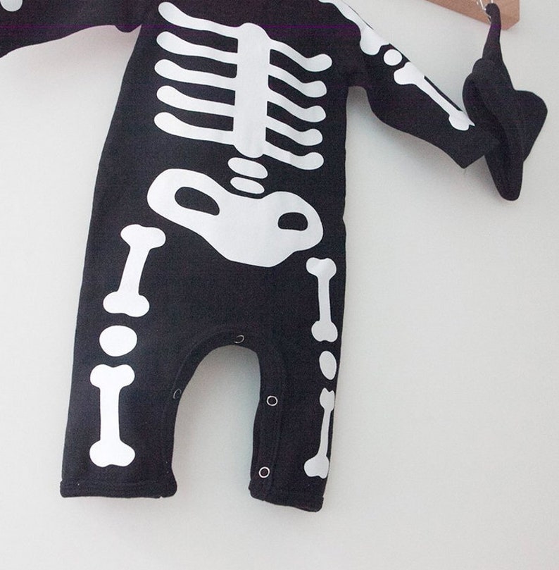 Op de afbeelding: Zwart-witte skelet onesie voor een baby. De onesie heeft een wit skelet ontwerp op een zwarte achtergrond.