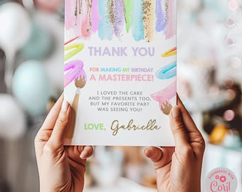 May include: A thank you card with a colorful paint splatter background and gold glitter accents. The text reads "Thank You for making my birthday a masterpiece! I loved the cake and the presents too, but my favorite part was seeing you! Love, Gabriella".